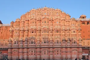 Facade of Hawa Mahal, a pink sandstone palace with intricate windows, in Jaipur during sunset.