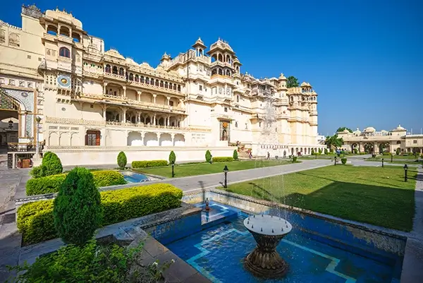 City Palace in Udaipur, India, with manicured gardens and clear blue sky.