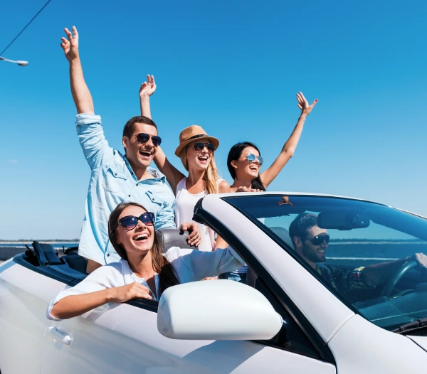 Group of friends enjoying a ride in a white convertible car on a sunny day.